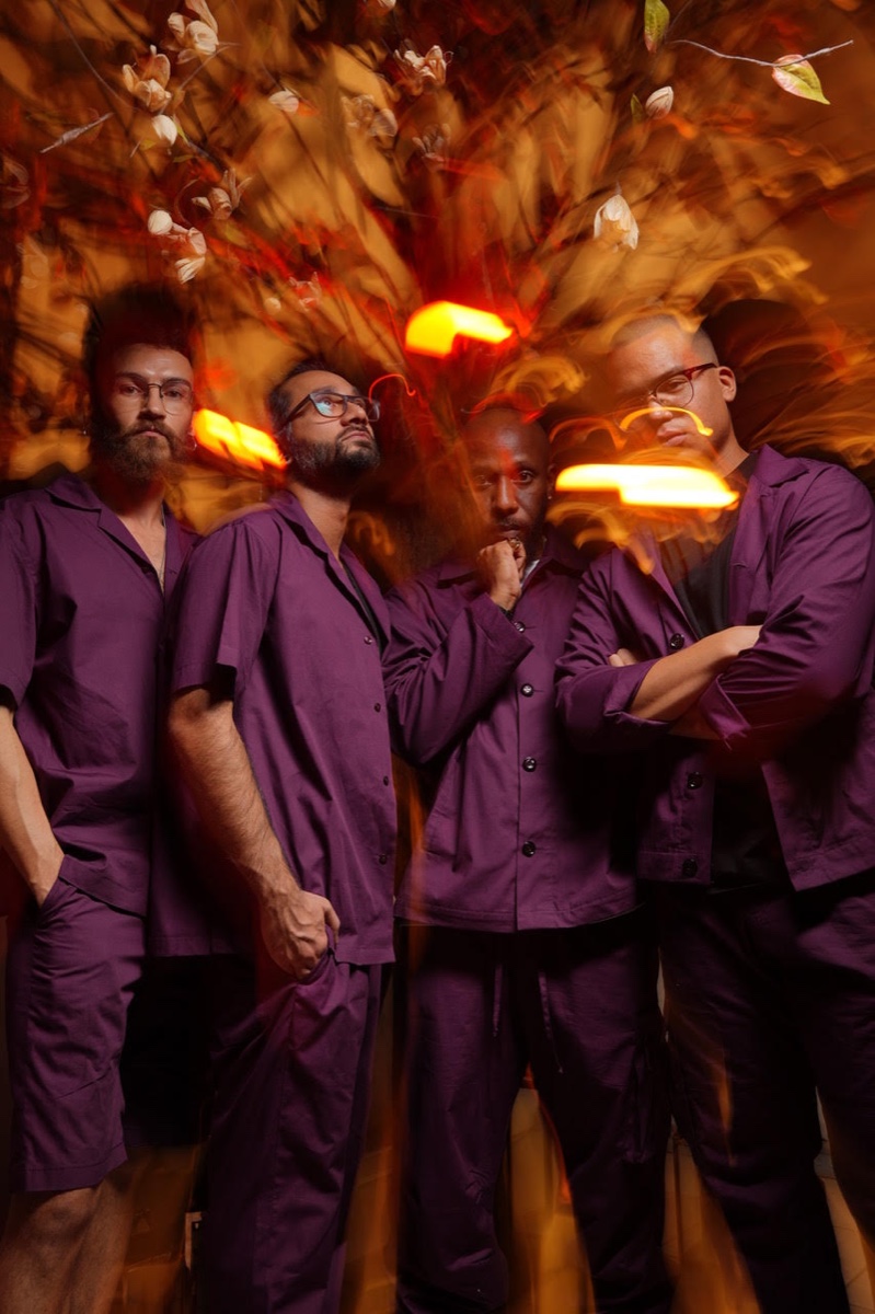 The band in purple, warm light behind them